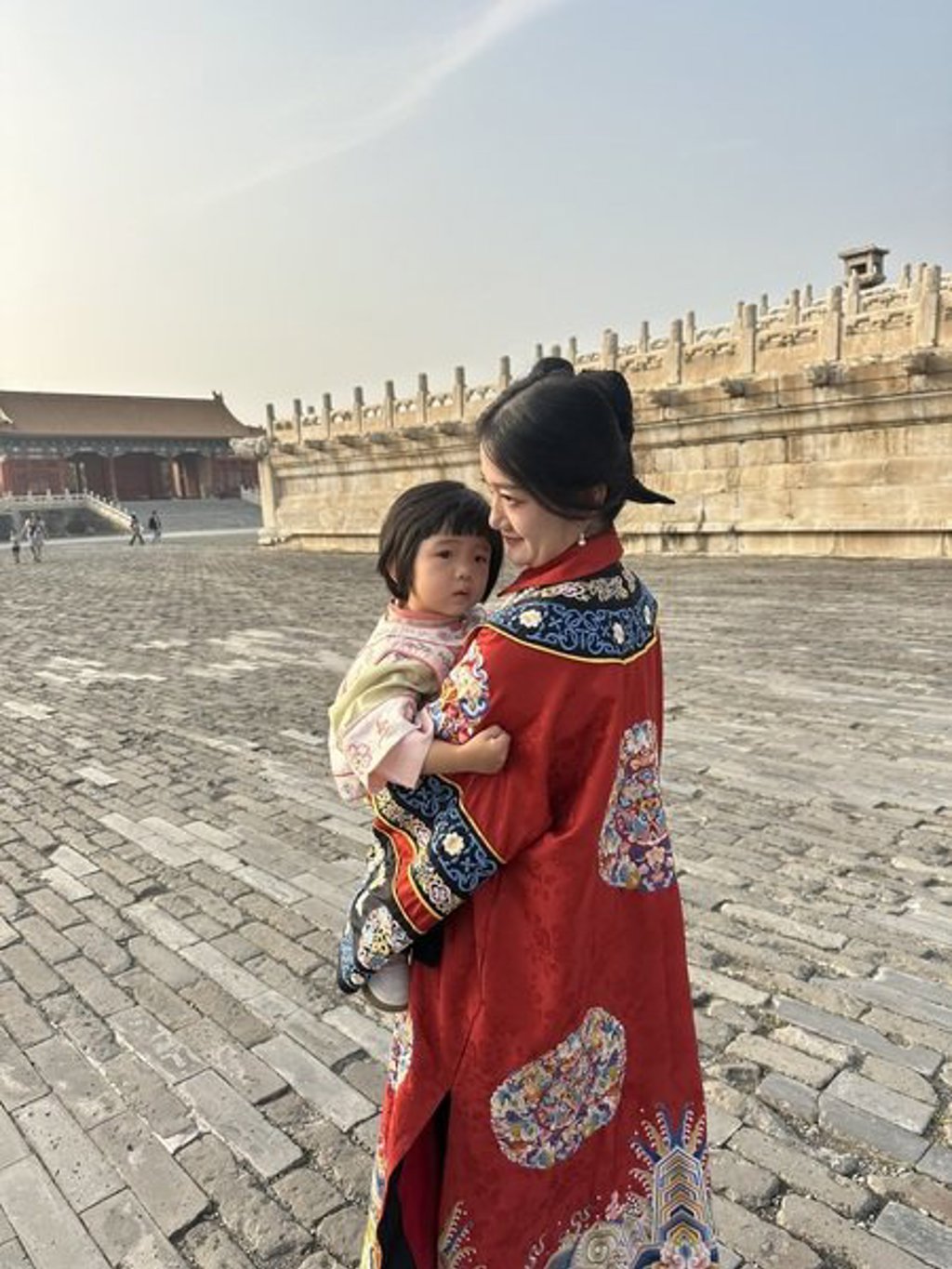 Chinese vrouw in traditionele kleding met kind in een paleiscomplex tijdens groepsrondreis China.