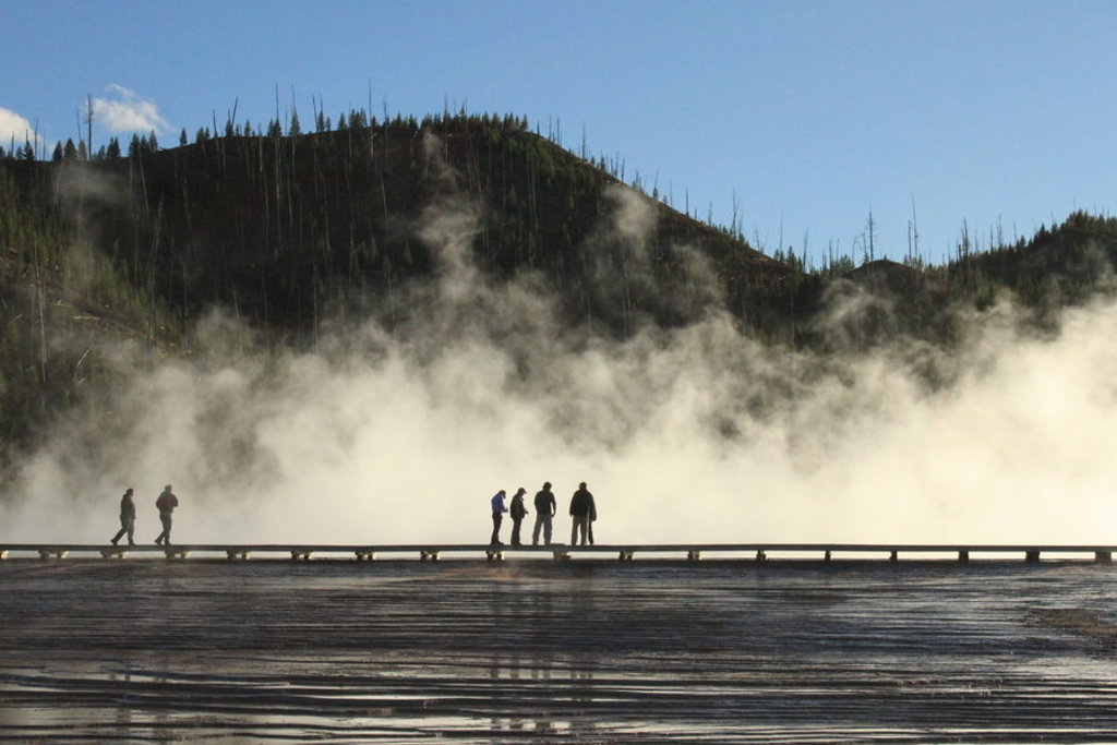 Reizigers wandelen langs een stomende geiser in Yellowstone National Park tijdens een groepsrondreis door Noordwest-USA.