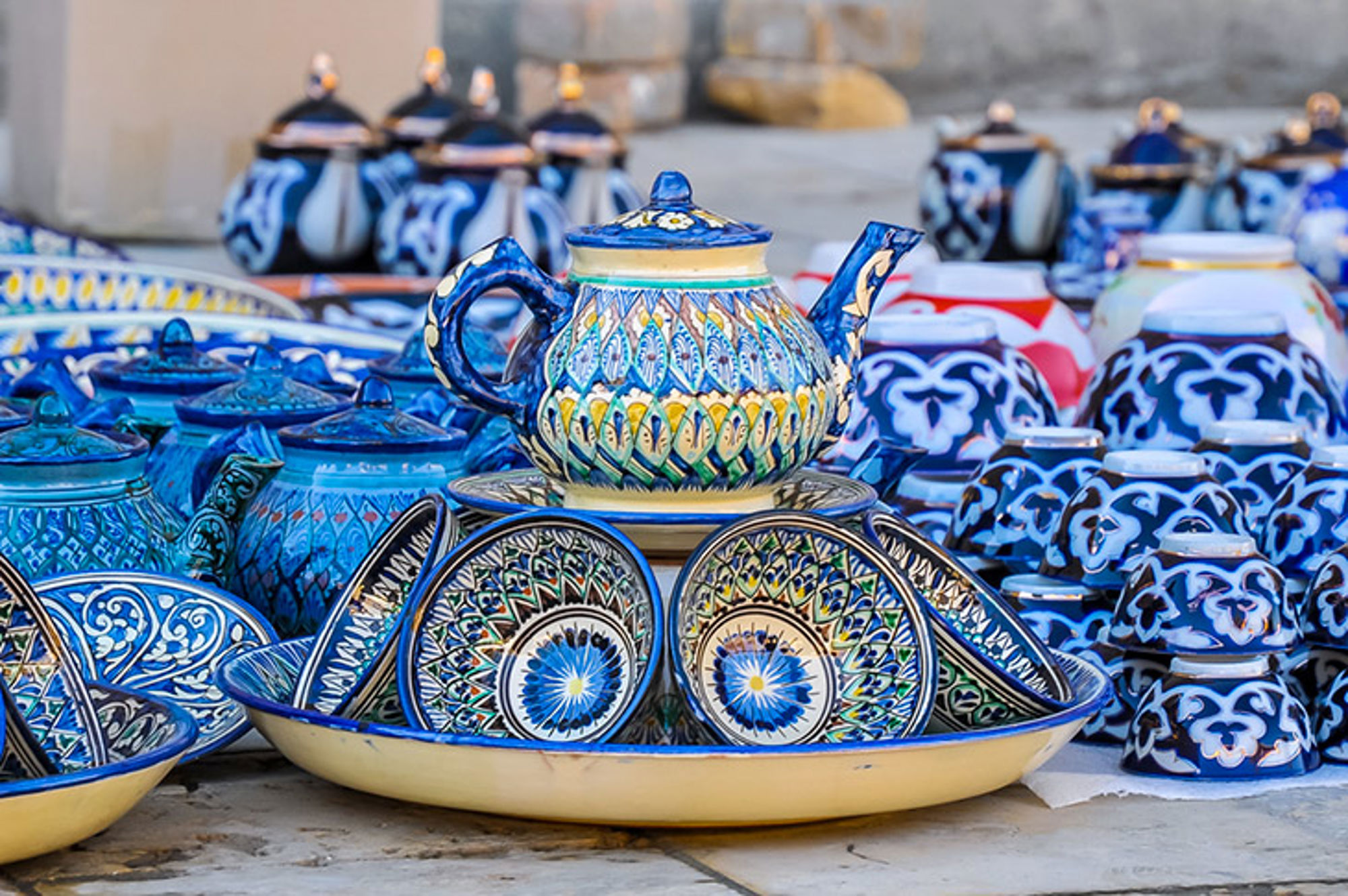 Servies in Oezbekistan Handbeschilderd blauw keramiek met theepot, schaaltjes en kommen op een markt.