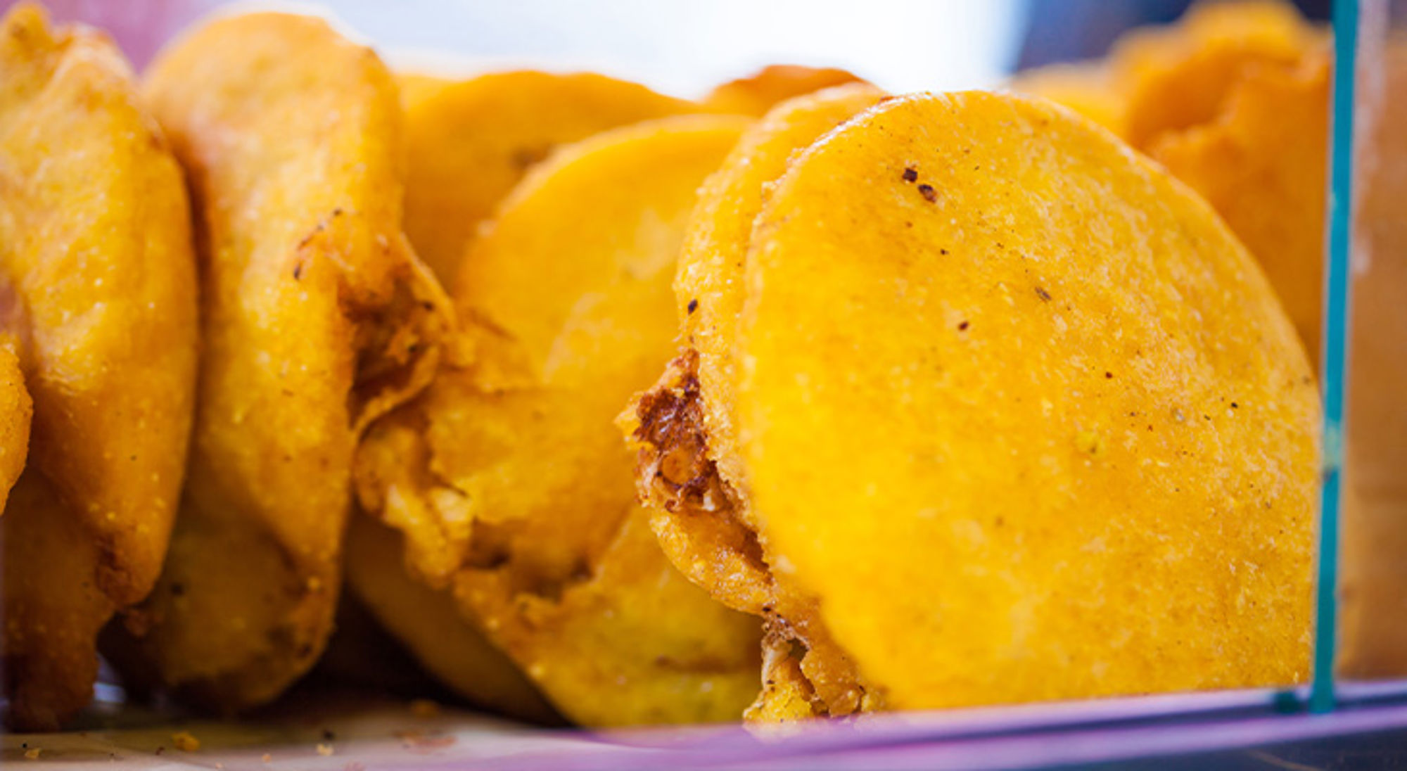 Arepa con huevo Cartagena Gele Surinaamse bara’s, vers gebakken en opgestapeld in een vitrine.
