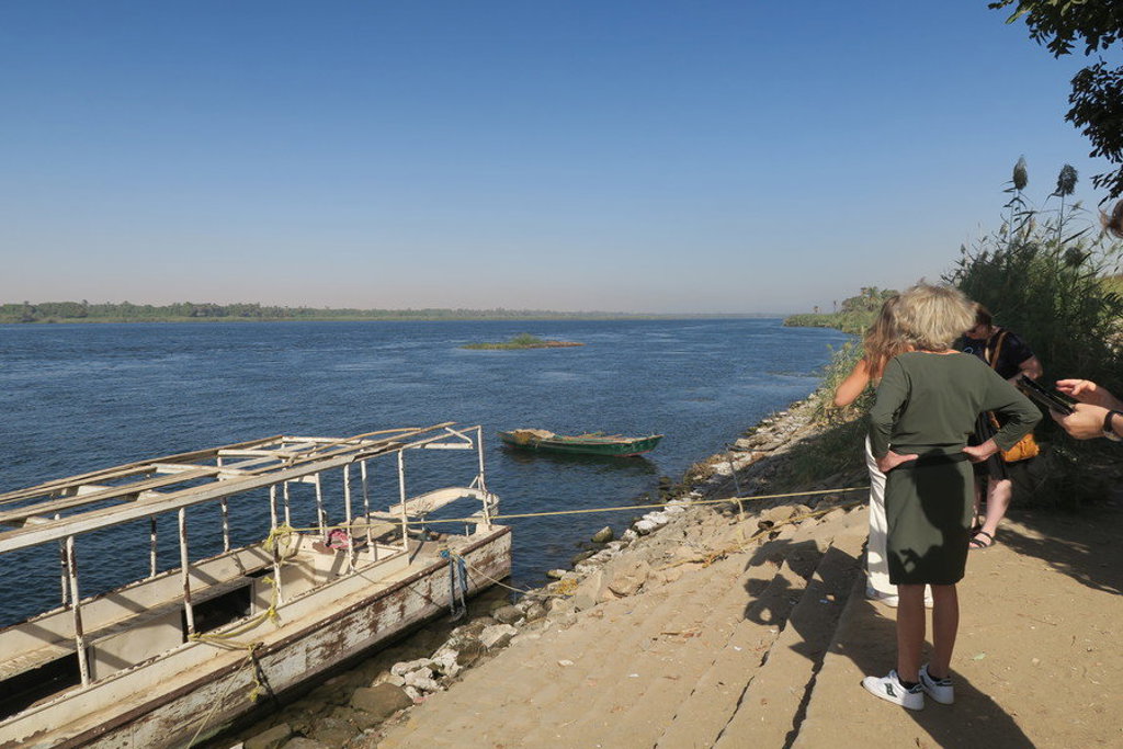 Reizigers aan de oever van de Nijl met aangemeerde boot tijdens een groepsrondreis Egypte.