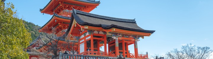 Kiyomizu-dera tempel in Kyoto met rode pagode en trappen onder een heldere blauwe lucht.