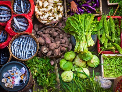 Kleurrijke markt in Bali met verse vis en groente zoals aubergines, kool, sperziebonen en pepers.