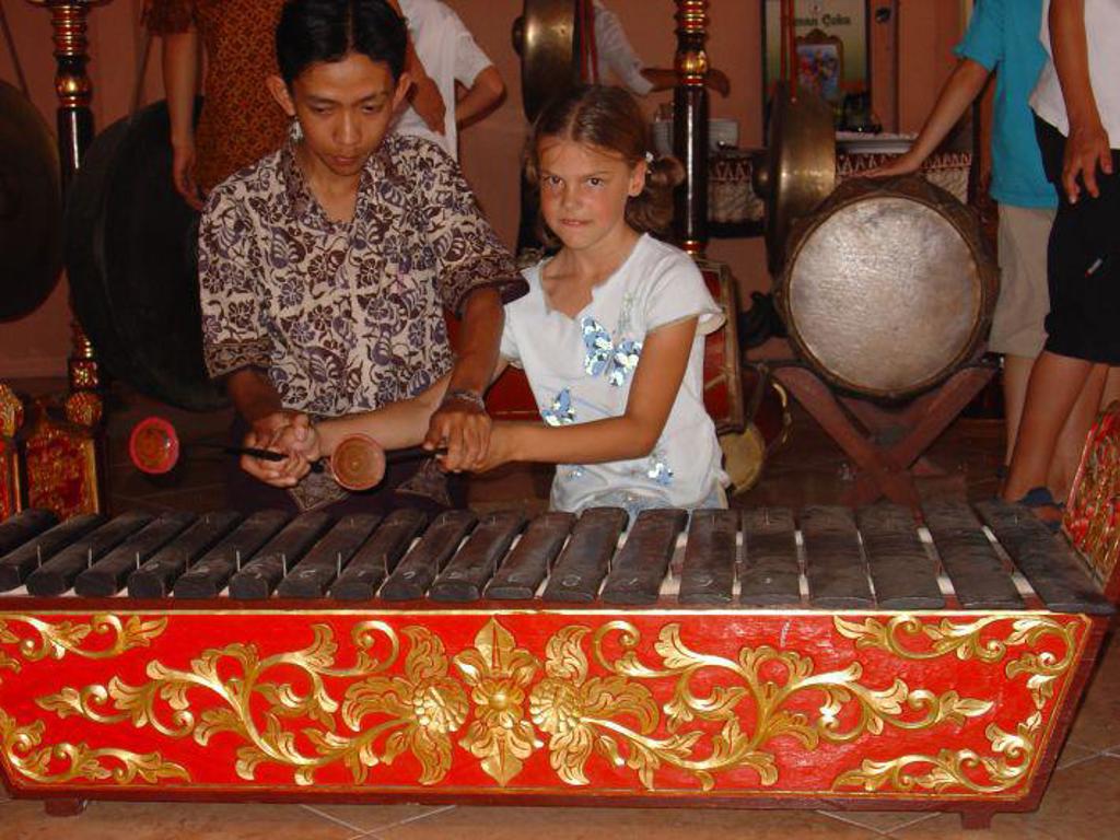 Meisje bespeelt een gamelan-instrument tijdens familiereis Java & Bali, Indonesië.