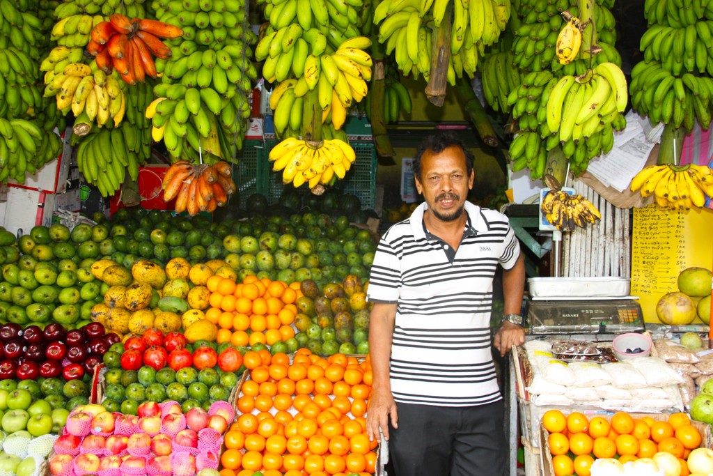Fruitkraam in Sri Lanka met verkoper, bananen en citrusvruchten tijdens een fietsvakantie.