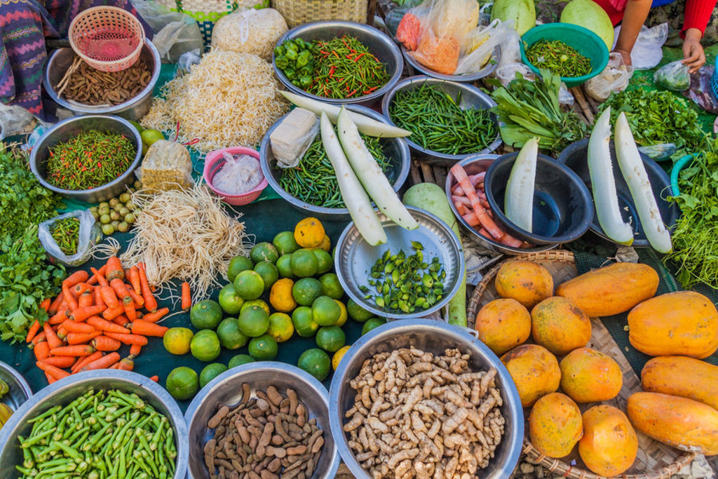 Kleurrijke markt in Myanmar met verse groenten, kruiden, noedels en fruit, tijdens een groepsrondreis Myanmar.