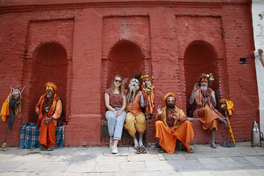 Reiziger poseert met sadhu’s bij een rode tempelmuur in Nepal tijdens een familiereis.