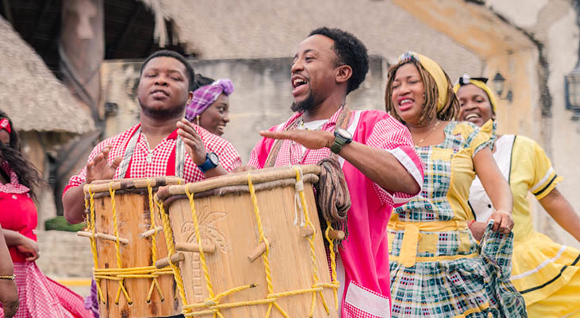 Lokale bevolking Belize Muzikanten en dansers in kleurrijke kleding spelen trommels tijdens een straatfestival.