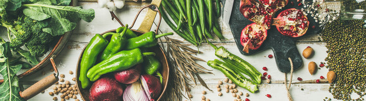 Verse groenten, peulvruchten, noten en granaatappel op tafel als inspiratie voor vegan reizen.