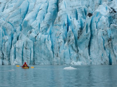 Kajakker peddelt langs een blauwe gletsjerwand in Alaska tijdens de Route Alaska.