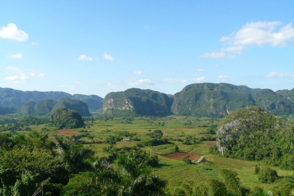 Groene vallei met mogotes en akkers in Cuba, gezien onder een blauwe lucht.