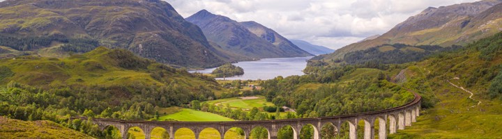 Glenfinnan-viaduct in de Schotse Hooglanden met bergen en loch op de achtergrond.