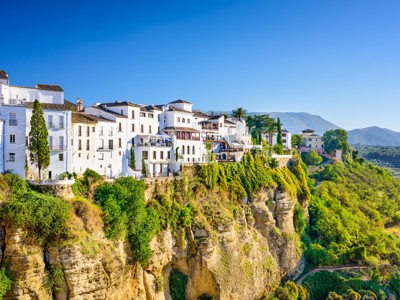 Witte huizen op de kliffen van Ronda in Andalusië, met uitzicht op groene vallei en bergen.
