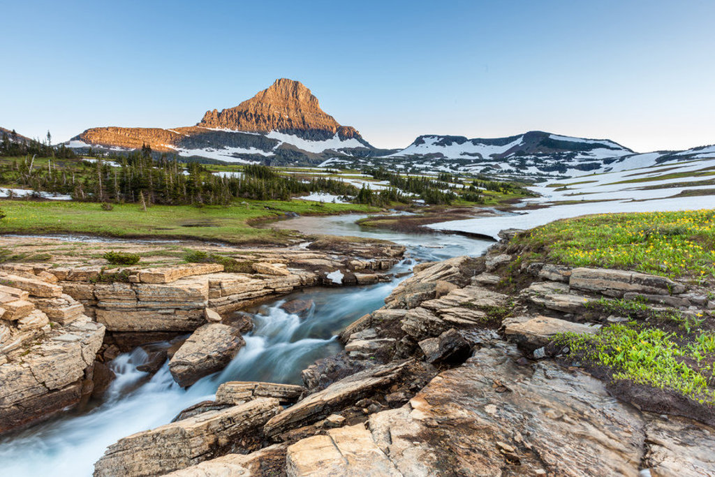 Berglandschap met smeltwaterbeek en sneeuwvelden in Glacier National Park, Verenigde Staten Noordwest.