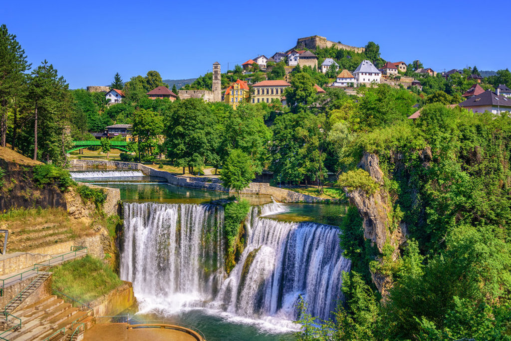 Waterval bij Jajce met middeleeuws fort en stad op de heuvel, highlight van de groepsrondreis Zuid-Oost Europa.