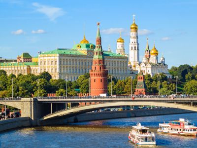 Uitzicht op het Kremlin in Moskou met brug over de rivier en rondvaartboten.