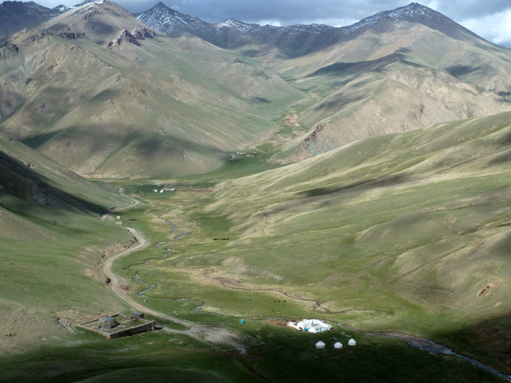 Groene bergvallei met rivier en yurts in Kirgistan tijdens groepsrondreis langs de Zijderoute.
