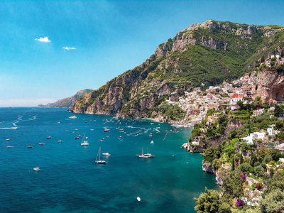 Uitzicht op Positano aan de Amalfikust met kleurrijke huizen op de kliffen en zeilboten in zee.