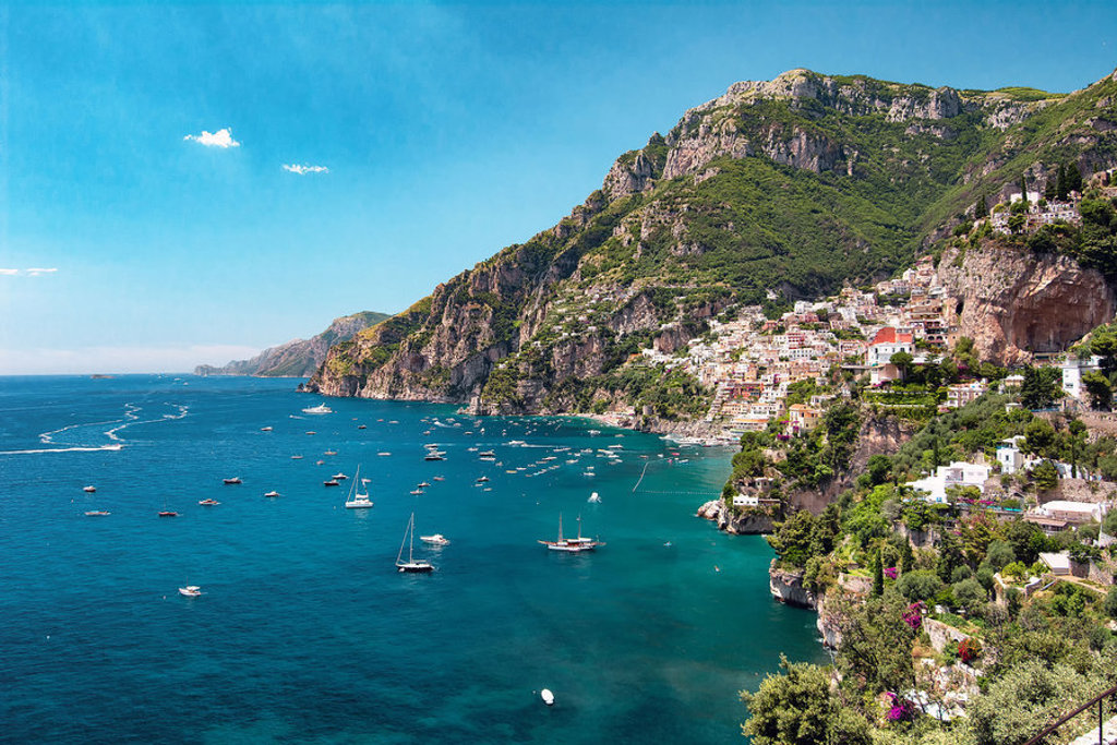 Uitzicht op Positano aan de Amalfikust met kleurrijke huizen op de kliffen en zeilboten in zee.