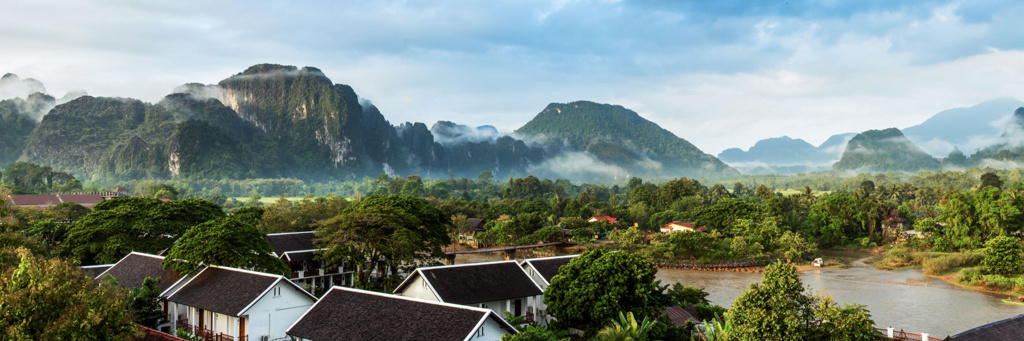 Karstbergen bij Vang Vieng in Laos, met rivier, groene vallei en mist in de ochtend.