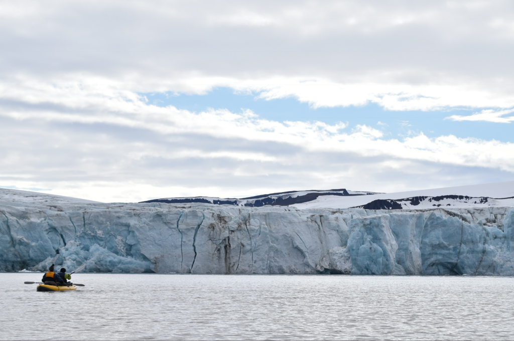 Kajakkers op zee bij een imposante gletsjer tijdens groepsrondreis van IJsland naar Groenland en Spitsbergen.