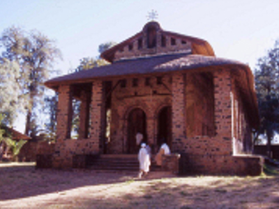 Rond Ethiopisch kerkgebouw met veranda en bezoekers bij de ingang, Route Ethiopië 29 dagen.