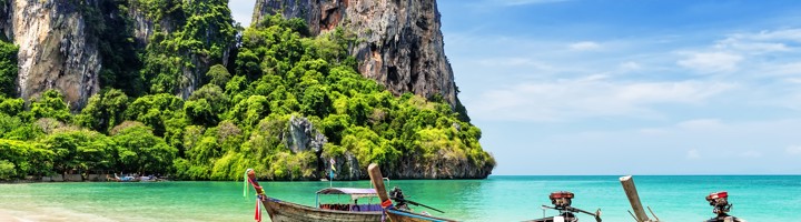 Longtailboten voor Railay Beach met kalkstenen kliffen en turquoise zee, Thailand.
