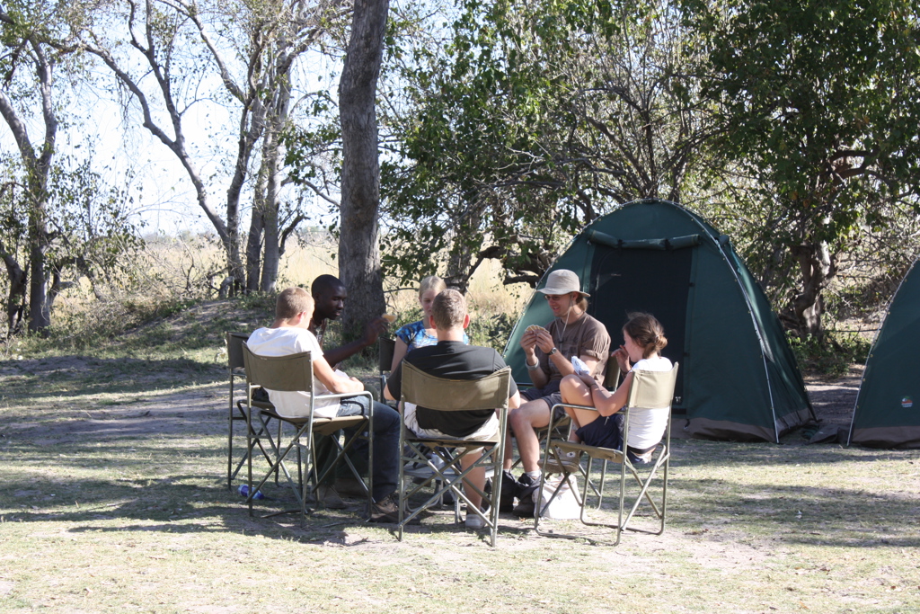 Reizigers spelen kaarten bij een kampeerplek met tenten in Zuidelijk Afrika tijdens familiereis Namibië, Botswana en Zimbabwe.