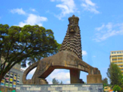 Leeuwenmonument in Addis Abeba, Ethiopië, met hoge zuil en stadsgebouwen op de achtergrond.