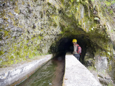 Wandelaar met helm bij een watertunnel langs een levada op Tenerife tijdens de 10-daagse wandelvakantie Tenerife & La Palma.