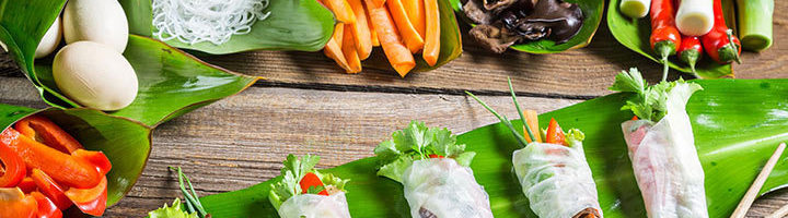 Vietnamese spring rolls met rijstnoedels en verse groenten op bananenblad.