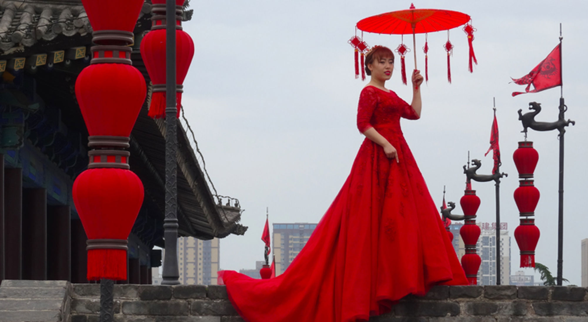 Lokale bevolking, fotoshoot, China Vrouw in rode jurk met parasol tussen rode lantaarns bij een traditionele tempel.