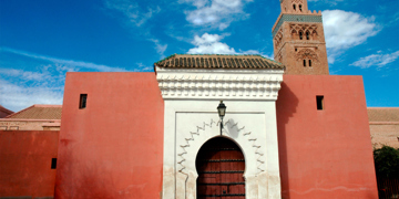 Toegangspoort met roze muren en minaret in Marrakech, Marokko.