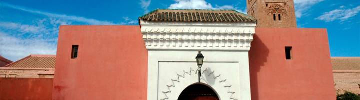 Toegangspoort met roze muren en minaret in Marrakech, Marokko.