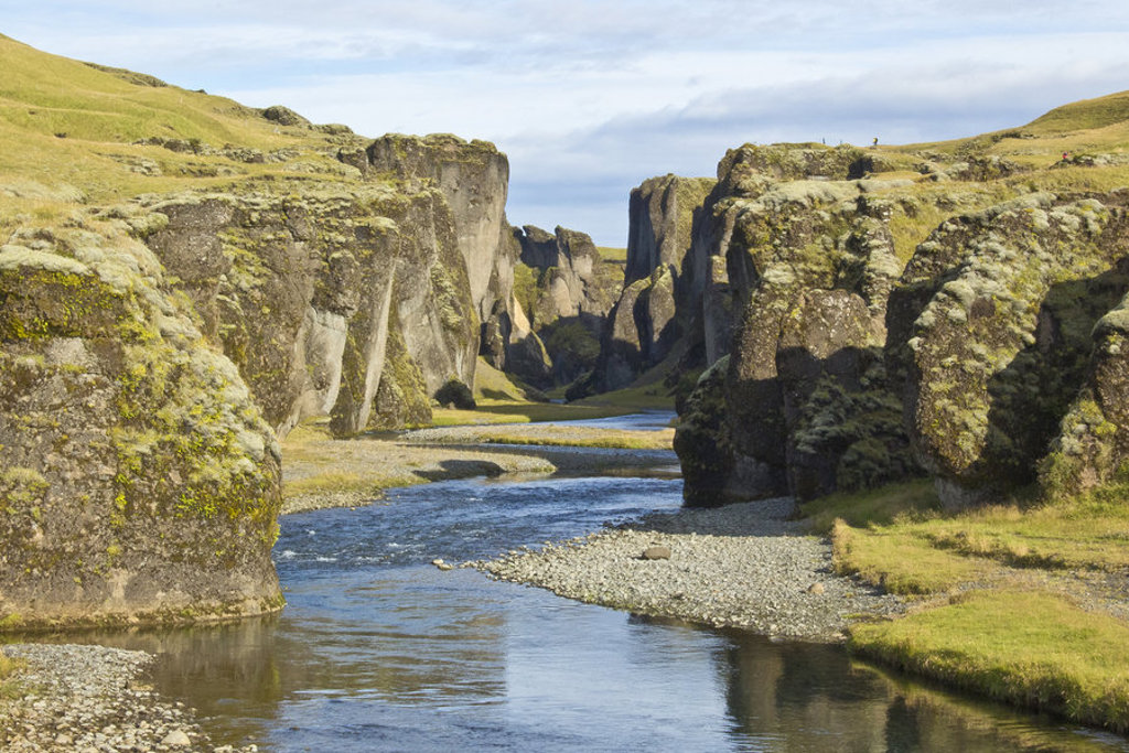 Groene kloof met rivier en steile rotswanden in IJsland tijdens een groepsrondreis kamperen.