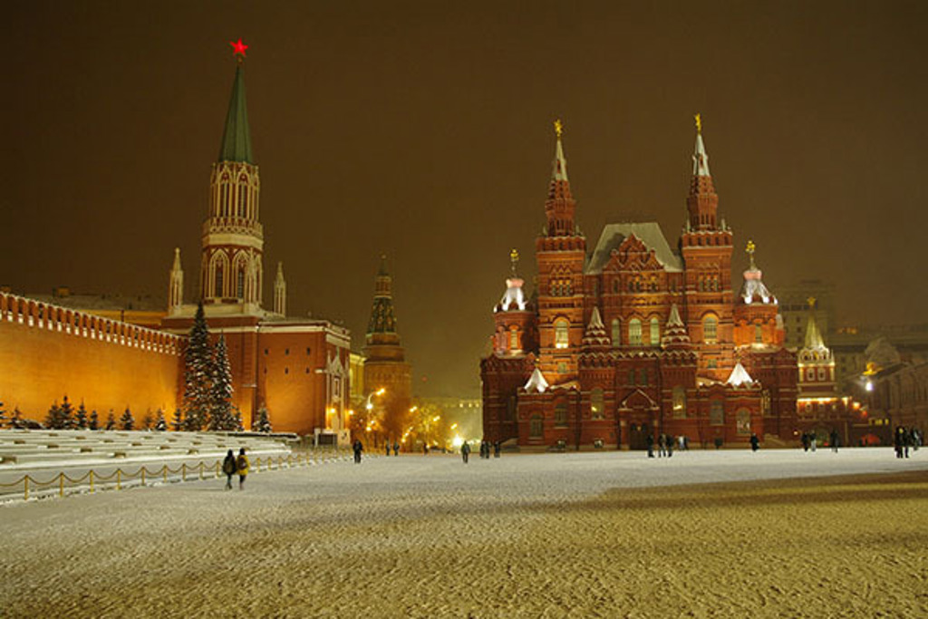 Verlicht Rode Plein in Moskou met het Historisch Museum en Kremlinmuur in de sneeuw, tijdens een winterrondreis Rusland.