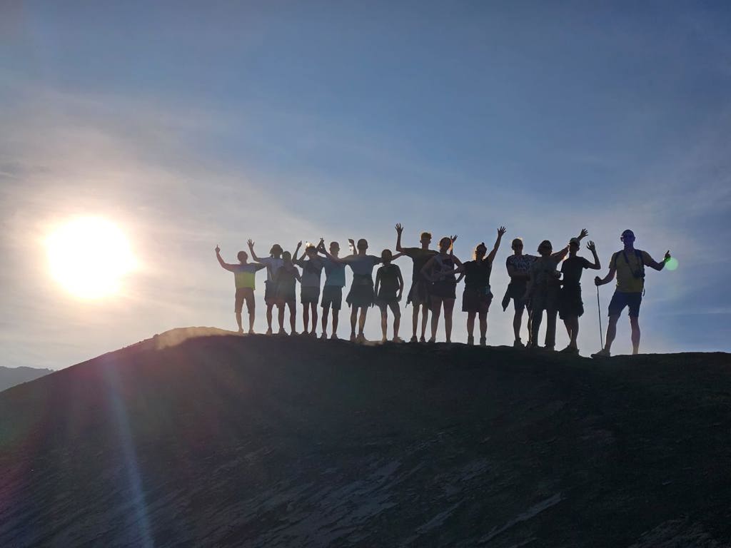Reizigers met opgeheven armen bij zonsopkomst tijdens Familiereis Java & Bali, Indonesië.