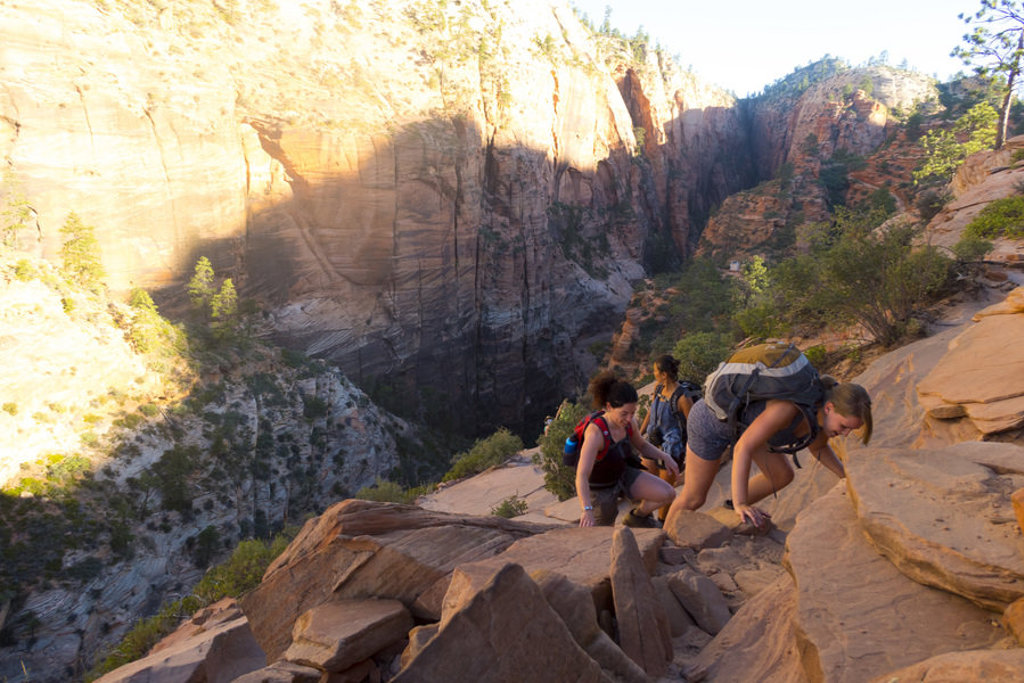 Wandelaars met rugzak klimmen over rotsen langs een diepe canyon in een nationaal park in de Verenigde Staten.