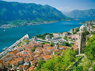 Uitzicht op de Baai van Kotor met oude stad, kerktoren en bergen langs het water tijdens de Route Balkan.