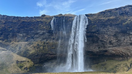 Waterval Seljalandsfoss in IJsland, met water dat van een klif naar beneden stort onder een blauwe lucht.