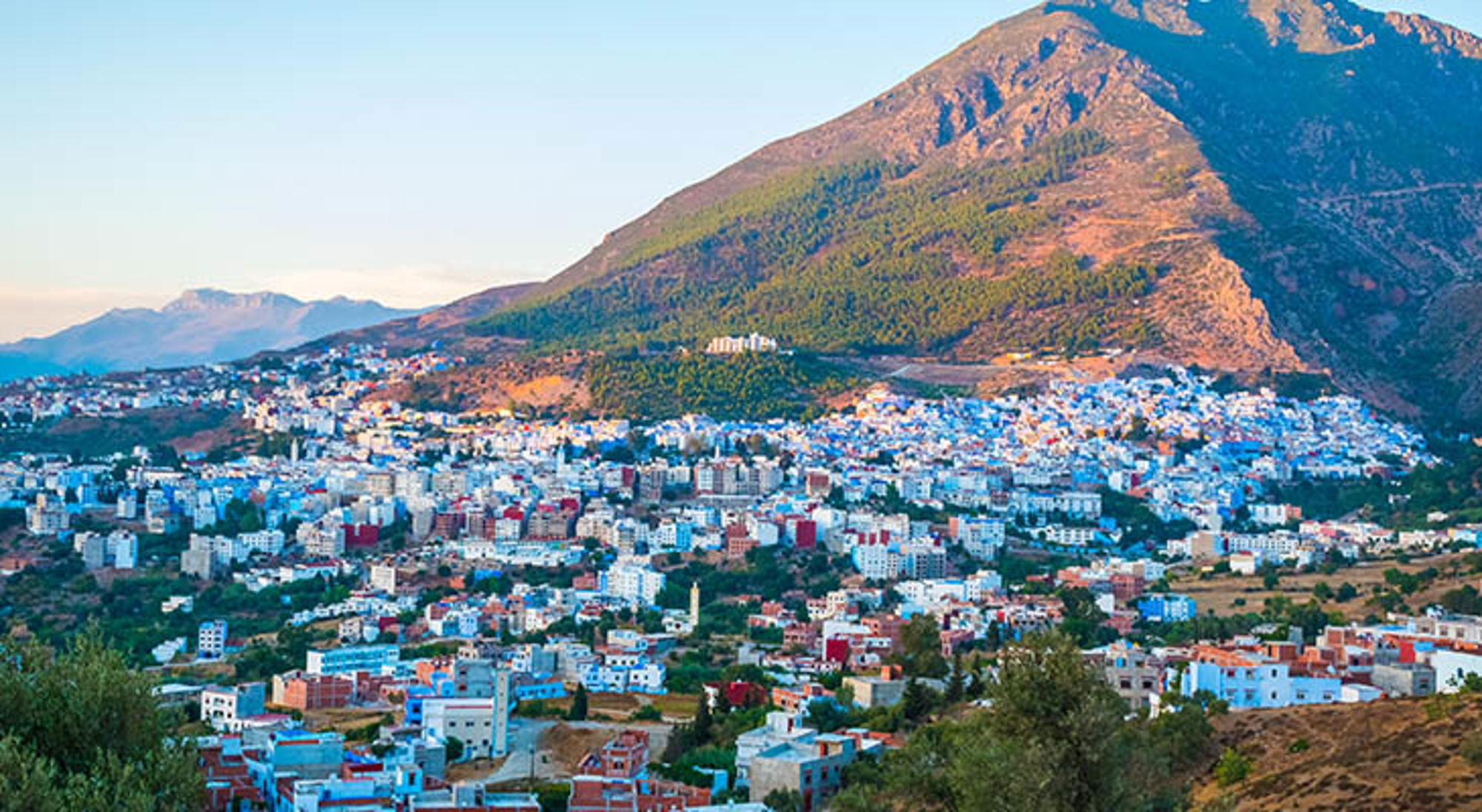 Rifgebergte Panorama van Chefchaouen met blauwgeschilderde huizen tegen de Rifbergen in Marokko.