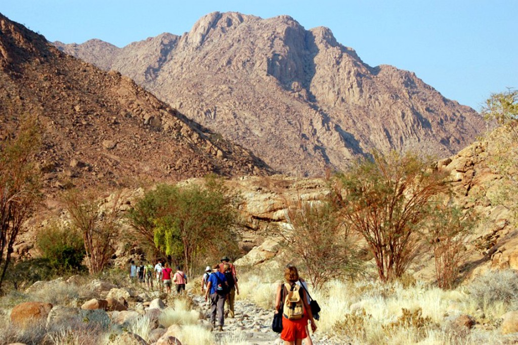 Wandelaars tijdens groepsrondreis Zuidelijk Afrika door rotsachtig berglandschap in Namibië.