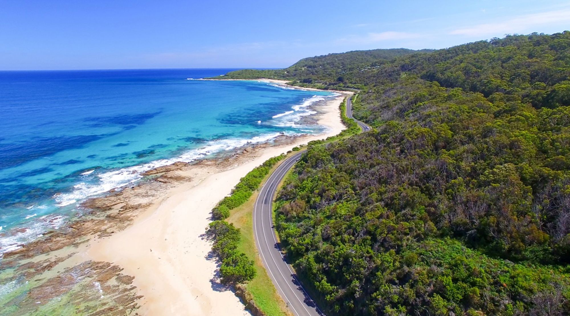 Kustweg langs strand en turquoise zee in Australië, gezien vanuit de lucht.
