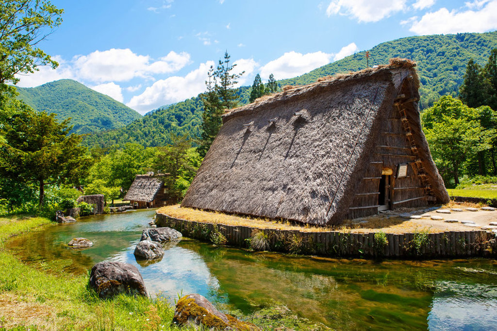 Traditioneel Japans rieten boerderijhuis bij een heldere rivier in de bergen, tijdens een familiereis Japan.