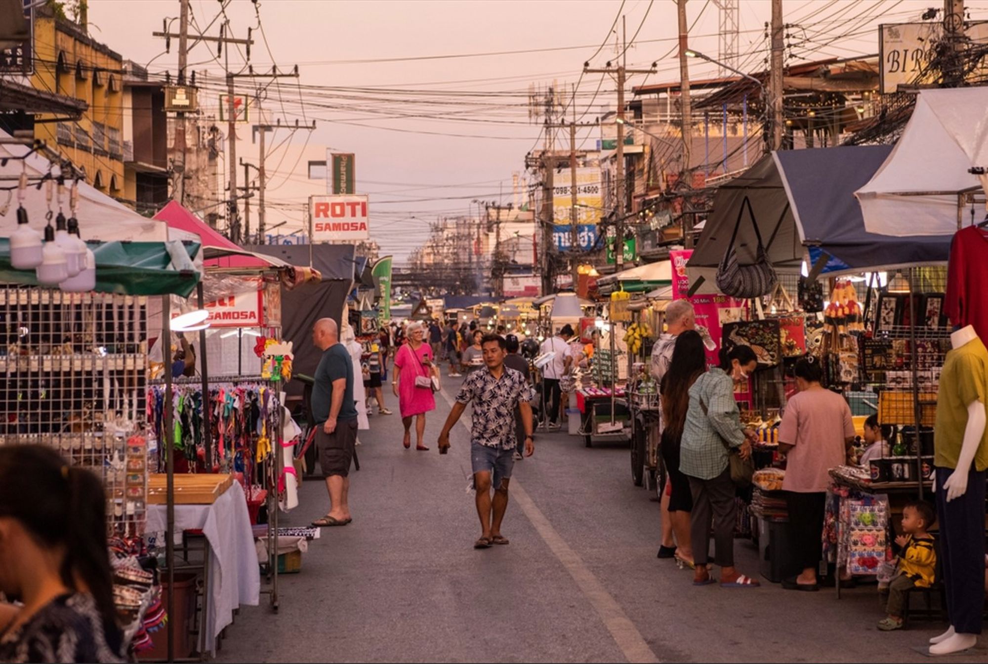 Avondmarkt in Thailand met kraampjes langs de straat en bezoekers die winkelen.