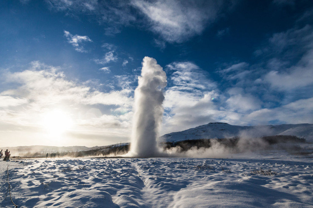 Geysir spuit heet water omhoog in een besneeuwd landschap tijdens een winter groepsrondreis door IJsland.