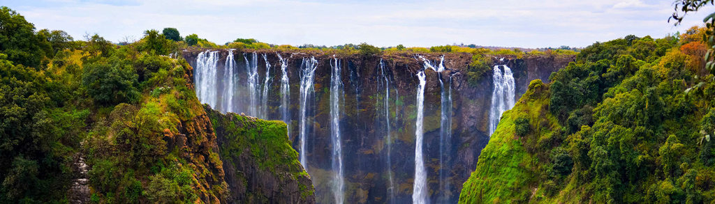 Panorama van de Victoria Falls met watervallen in een groene kloof tijdens groepsrondreis Zuidelijk Afrika.