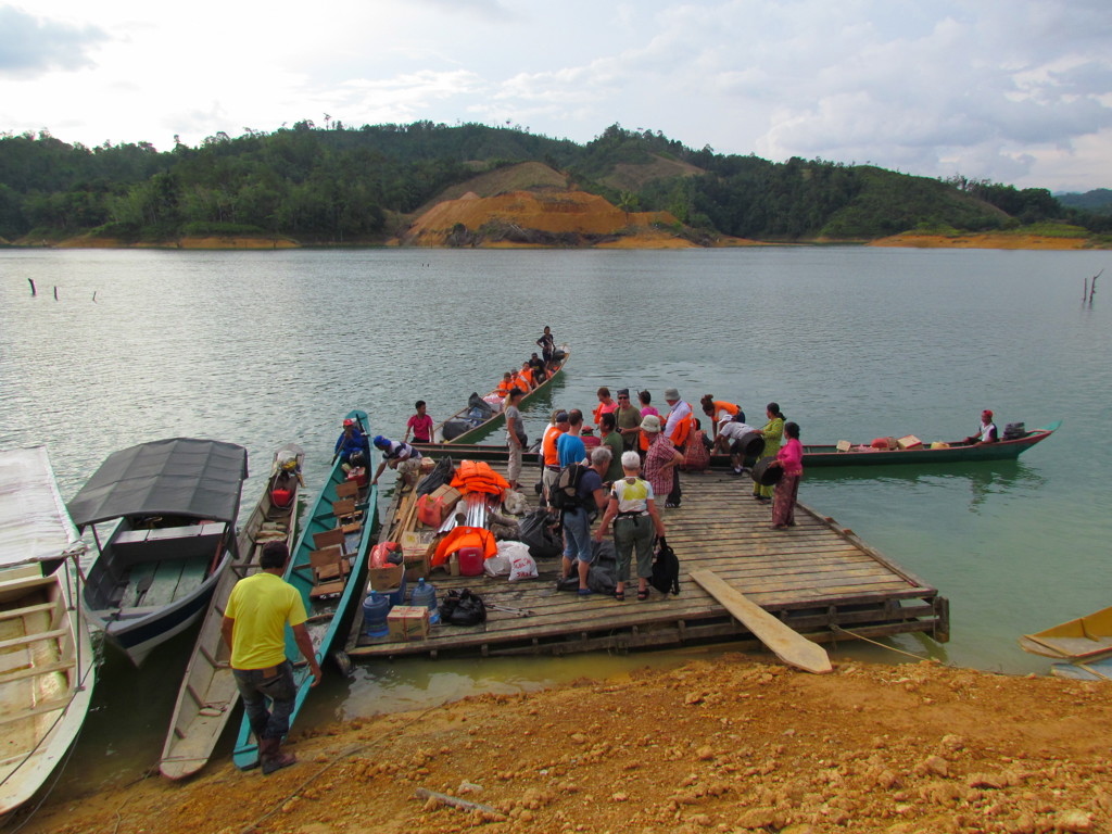 Reizigers stappen in longboats bij een steiger op een meer in Maleisisch Borneo.
