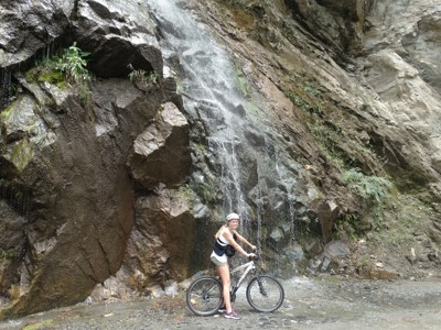 Fietser bij waterval langs rotswand tijdens Route Ecuador.