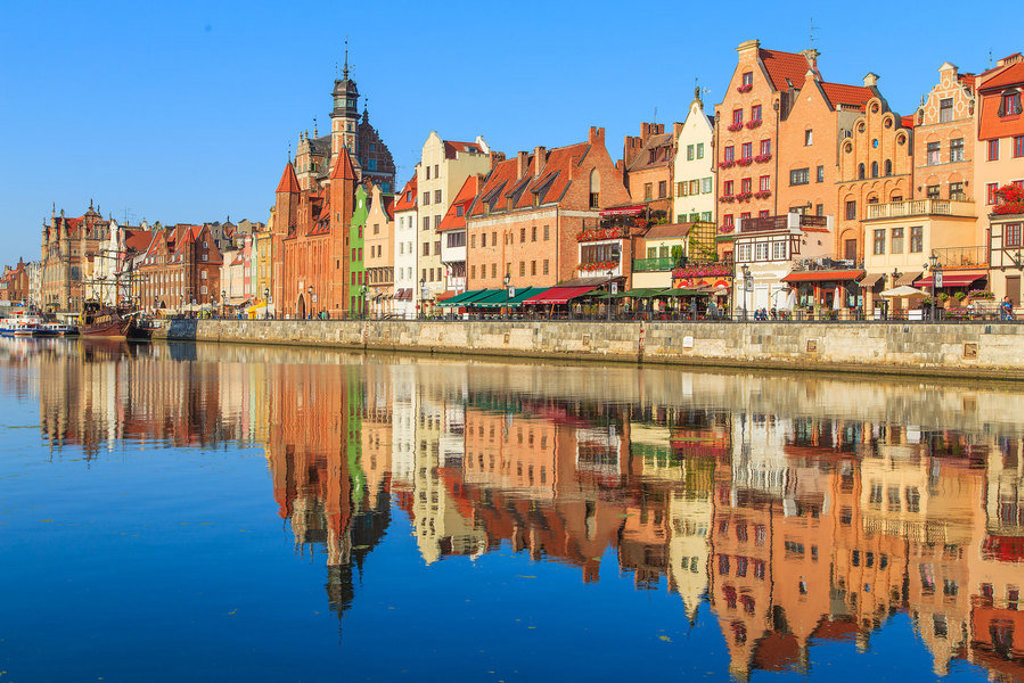 Kleurrijke gevels en oude haven aan de Motława in Gdańsk, Polen, met weerspiegeling in het water.